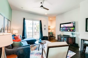 A modern living room with a sofa, armchair, and coffee table. There is a TV mounted on the wall and a ceiling fan. - Nashville rooftop deck & game room house, sleeps 10 near broadway (Nashville)
