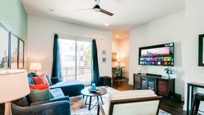 A modern living room with a sofa, armchair, and coffee table. There is a TV mounted on the wall and a ceiling fan. - Music-themed Nashville home with game room, bar & bunk rooms, sleeps 10 (Nashville)