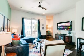 A modern living room with a sofa, armchair, and coffee table. There is a TV mounted on the wall and a ceiling fan. - Nashville game room & bar house, sleeps 10, 3BR near Parthenon (Nashville)