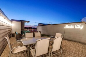 An outdoor patio area with a table and chairs, a neon sign reading "Music City," and a brick floor. - Nashville game room & bar house, sleeps 10, 3BR near Parthenon (Nashville)
