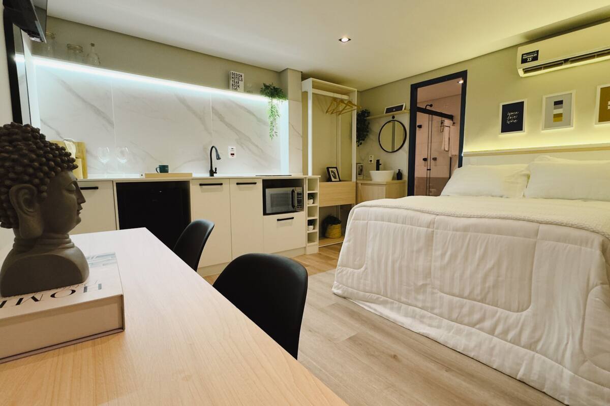 Une chambre d’hôtel moderne équipée d’un lit, d’un bureau, d’une chaise, d’un four à micro-ondes, d’un lavabo et d’un miroir.