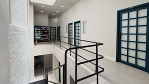 Een meerlaags interieur met een trap, een boekenkast en een grote deur met geëtste glazen panelen.
