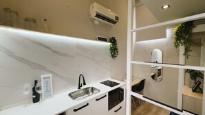 Een moderne keuken met een wit aanrecht, een ingebouwde oven en een spoelbak. Er staan wijnglazen en een fles op het aanrecht.