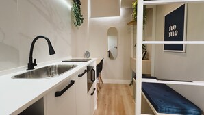 Een kleine keuken met een spoelbak, kastjes en een spiegel.