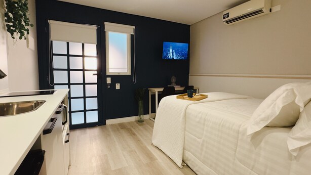 Een moderne hotelkamer met een bed, een bureau en een televisie aan de muur.