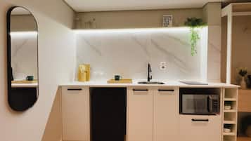 A modern kitchen with white cabinets, a black dishwasher, a microwave, and a sink.