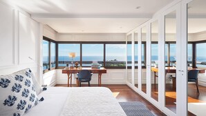 A bedroom with a large bed, a desk, and a view of the ocean. - Luxury Ocean View Apartment by Portugal Portfolio (Cascais)