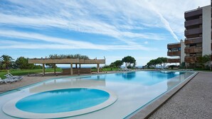 A swimming pool with lounge chairs, a covered area, and a view of the sea. - Luxury Ocean View Apartment by Portugal Portfolio (Cascais)