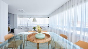 A modern meeting room with a glass table, wooden center, and white chairs. - Luxury Ocean View Apartment by Portugal Portfolio (Cascais)