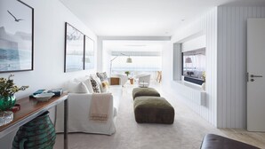 A modern living room with a sofa, ottomans, a coffee table, and a view of the outdoors through large windows. - Luxury Ocean View Apartment by Portugal Portfolio (Cascais)