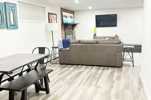 Relax in this stylish living room with a large sofa, flat-screen TV, and dining table.