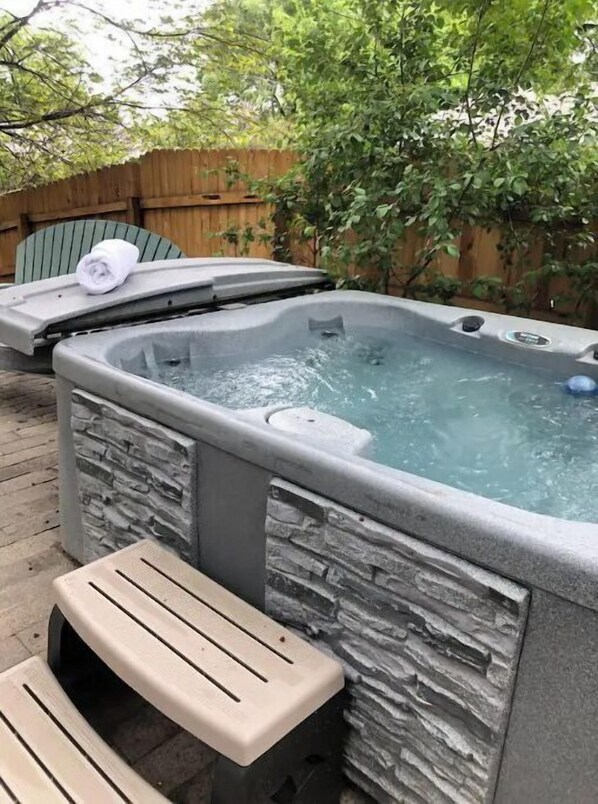 Relax in a hot tub surrounded by a serene outdoor patio.
