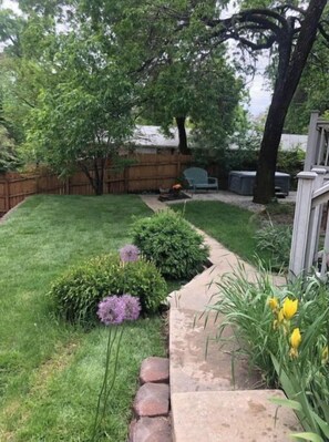 Enjoy a serene outdoor space surrounded by lush plants and a small garden, accessible via a stone pathway.