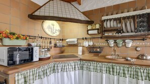Une cuisine équipée d’un four à micro-ondes, d’ustensiles suspendus et d’un dosseret carrelé.