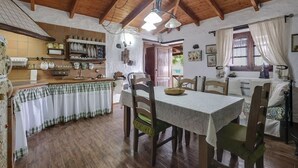 Une cuisine rustique avec des poutres en bois, une table à manger avec des chaises et un plan de travail avec de la vaisselle et des ustensiles.