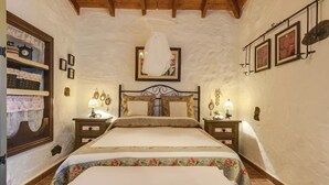Une chambre à coucher avec un lit, deux tables de chevet, une horloge murale et un tableau encadré.