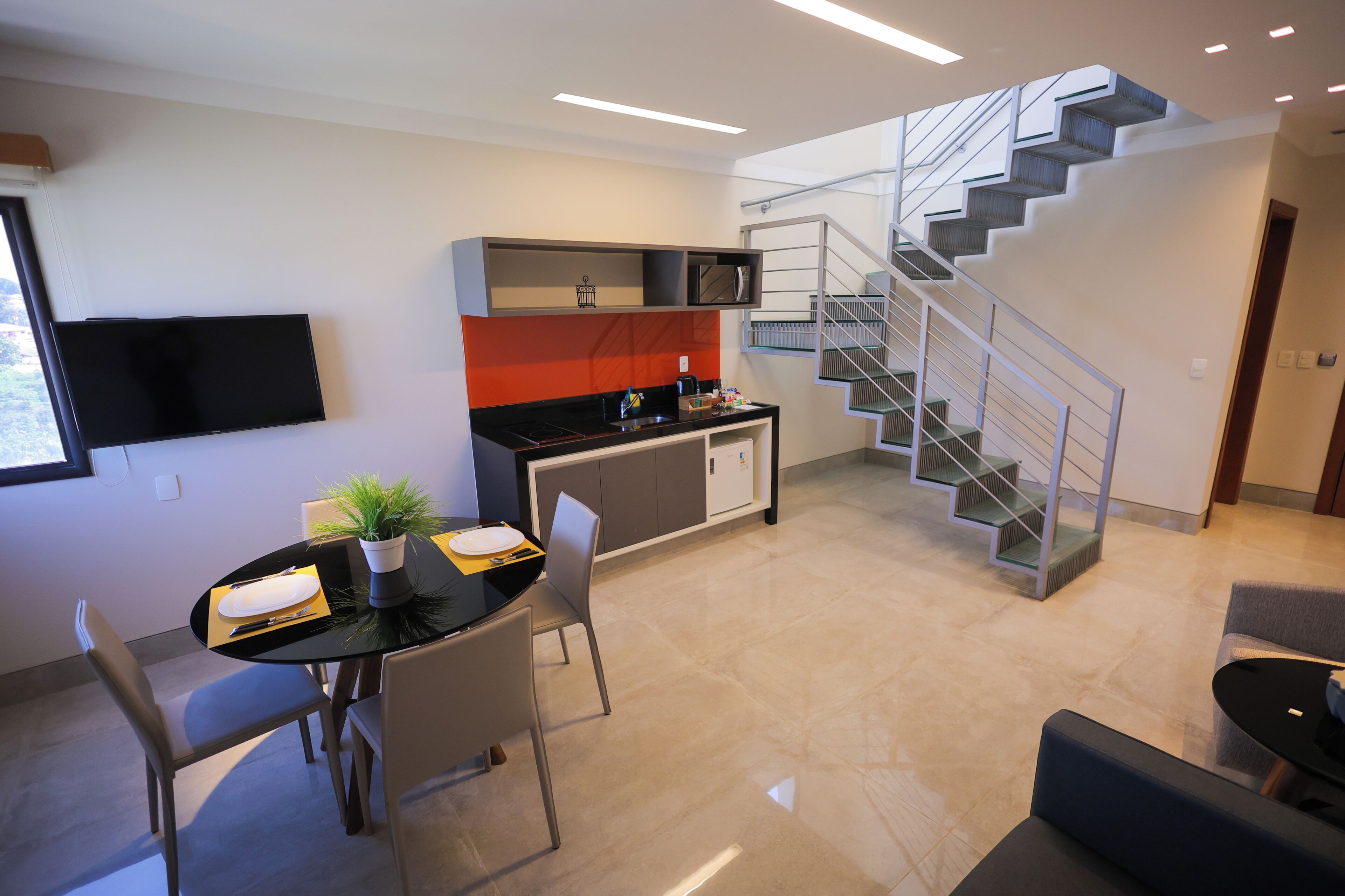 Una cocina moderna con comedor, una escalera y un televisor de pantalla plana.