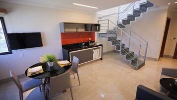 Una cocina moderna con comedor, una escalera y un televisor de pantalla plana.