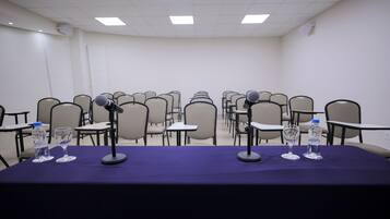 A conference room with a long table, multiple chairs, microphones, and water bottles.
