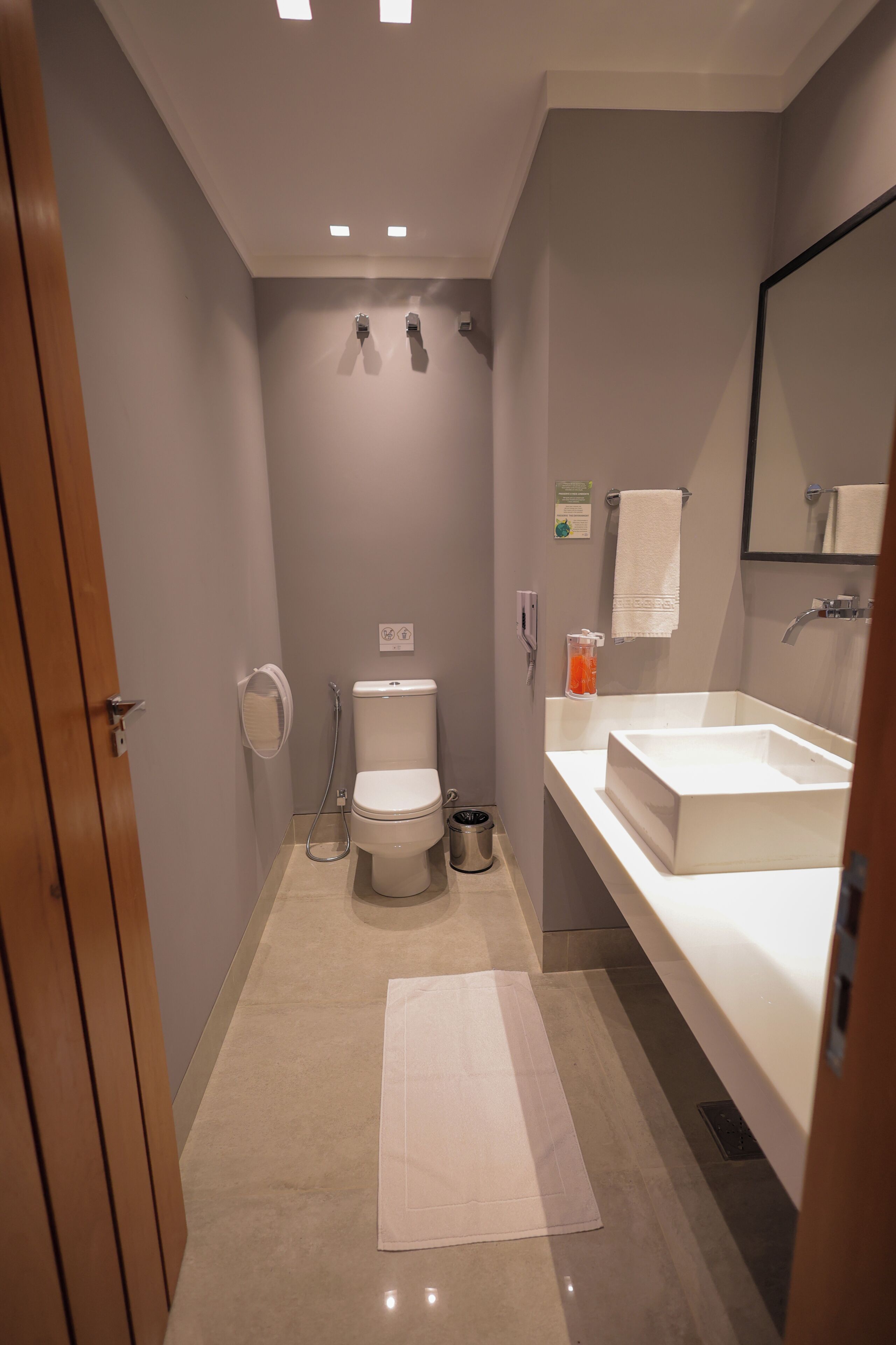 A bathroom with a toilet, sink, mirror, and towel rack.