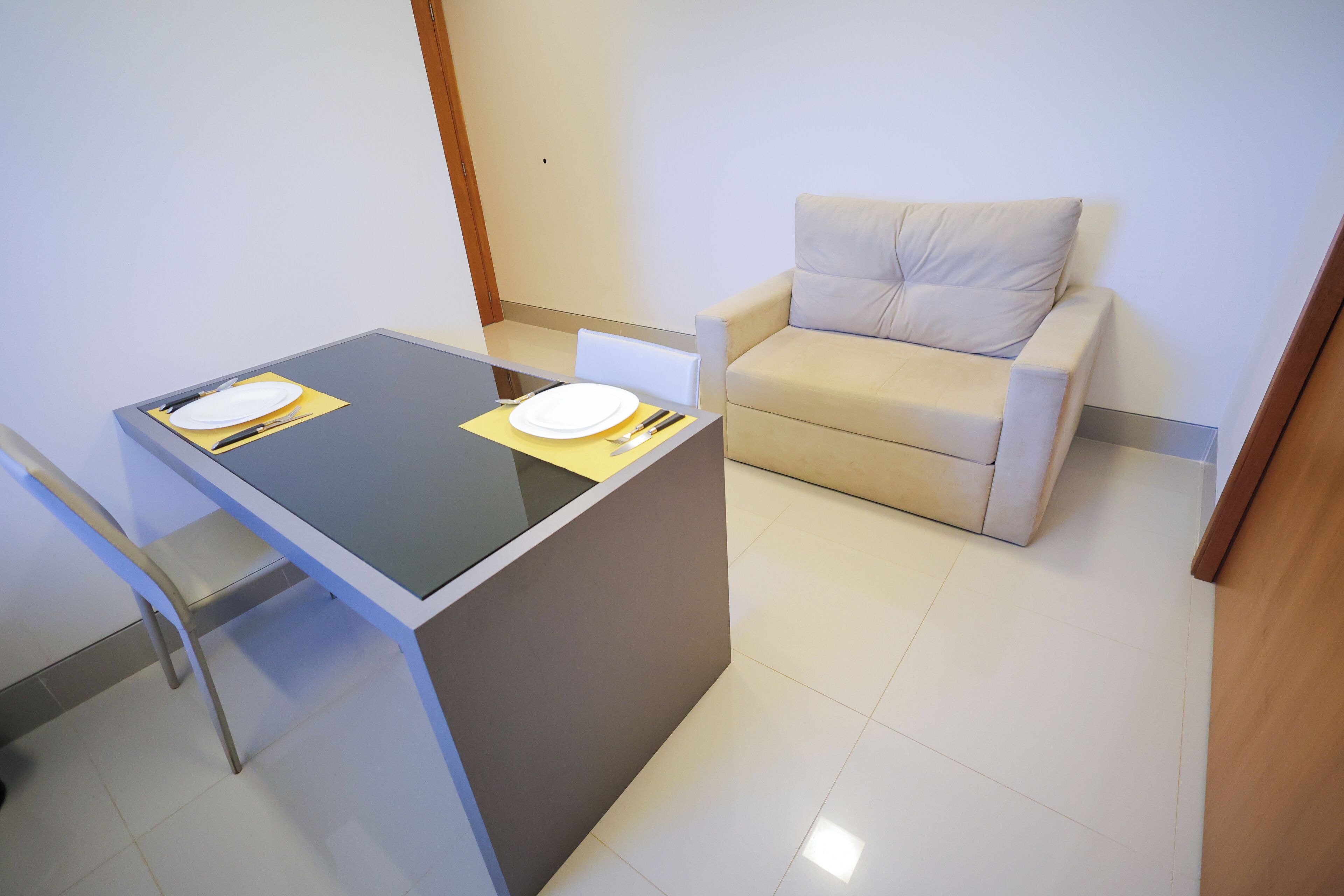 Una habitación pequeña y moderna con una mesa de comedor, un sofá y una silla.