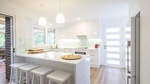 Enjoy cooking in this well-equipped kitchen with a central island, white cabinetry, and pendant lights.