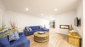 Relax in this stylish living room with a blue sofa, round coffee table, and flat-screen TV.
