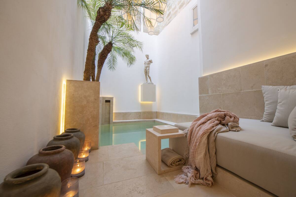 A spa area with a pool, a sofa, and a statue.