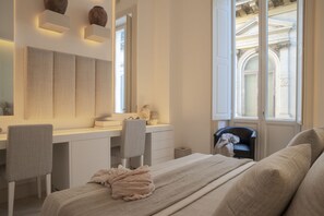 A bedroom with a bed, a desk, and a chair. There is a window with a view of a building. - Palazzo Lecce - Epoca Collection (Lecce)