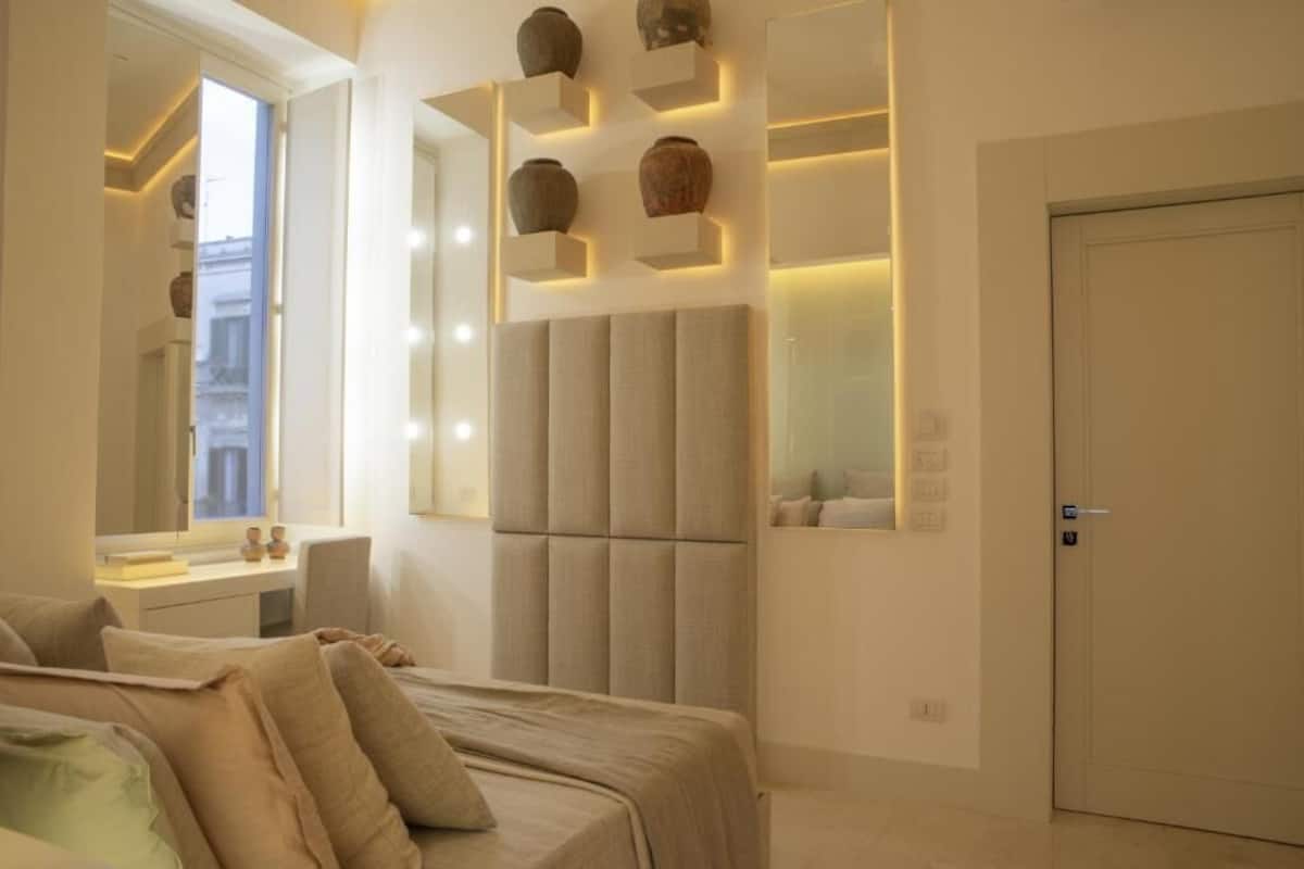 A modern bedroom with a bed, bedside table, and a large mirror.