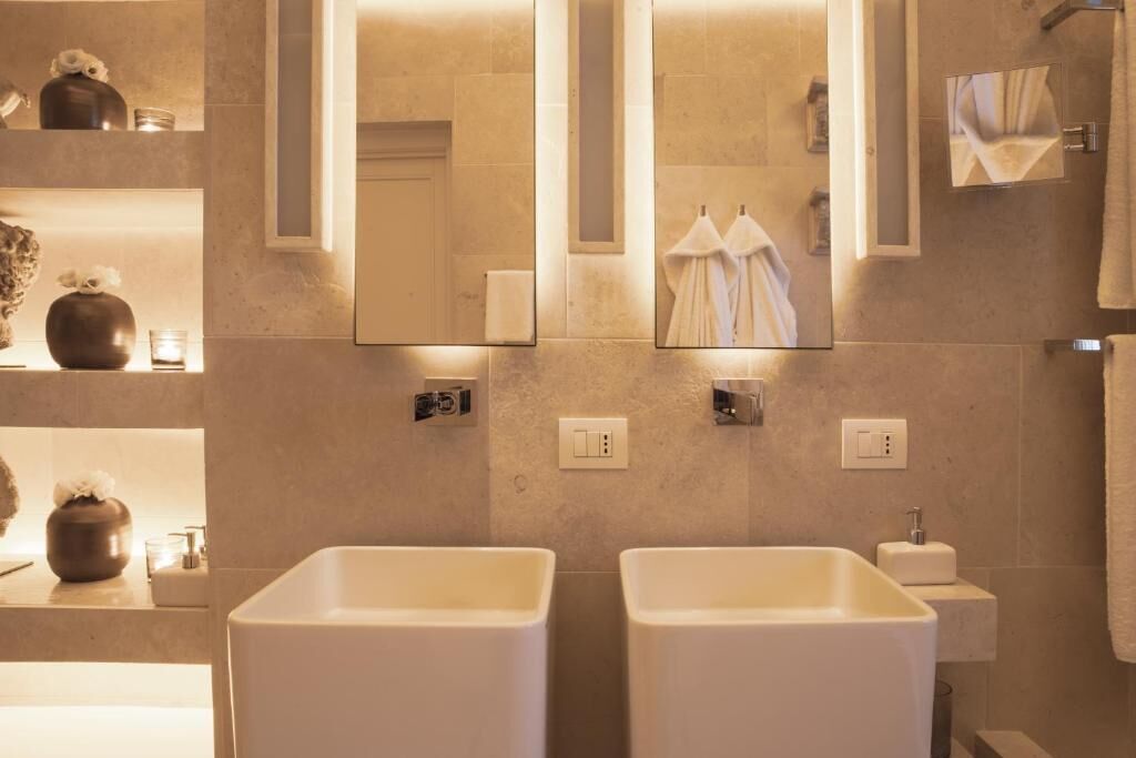 A modern bathroom with two sinks, a mirror, and a towel rack.