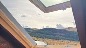 A skylight in a room with a view of a hilly landscape.