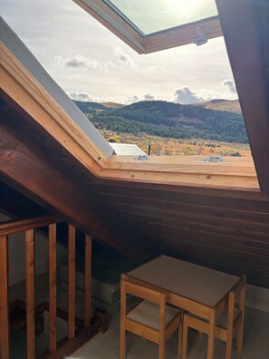 A skylight in a room with a view of a hilly landscape.