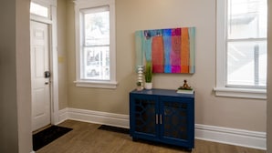 A hallway with a blue cabinet, a colorful abstract painting, and a white door. - *5 Min to WVU*Smart TV*Full Kitchen*W/D (Morgantown)