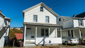A two-story white house with a front porch, a garage, and a car parked in front. - *5 Min to WVU*Smart TV*Full Kitchen*W/D (Morgantown)