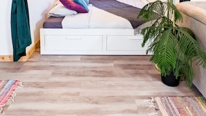 Un dormitorio con cama, cortinas, ventana, lámpara y planta.
