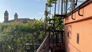 A balcony with a wrought iron railing, a tiled floor, and a view of a building with two domed towers in the background. - Incantevole Attico in Via Del Corso (Roma)