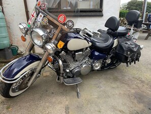 Uma motocicleta estacionada em frente a um edifício, com diversos adesivos no guidão.