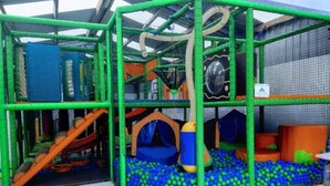 Een speelruimte met een netstructuur, glijbanen, tunnels en een balseizoen.