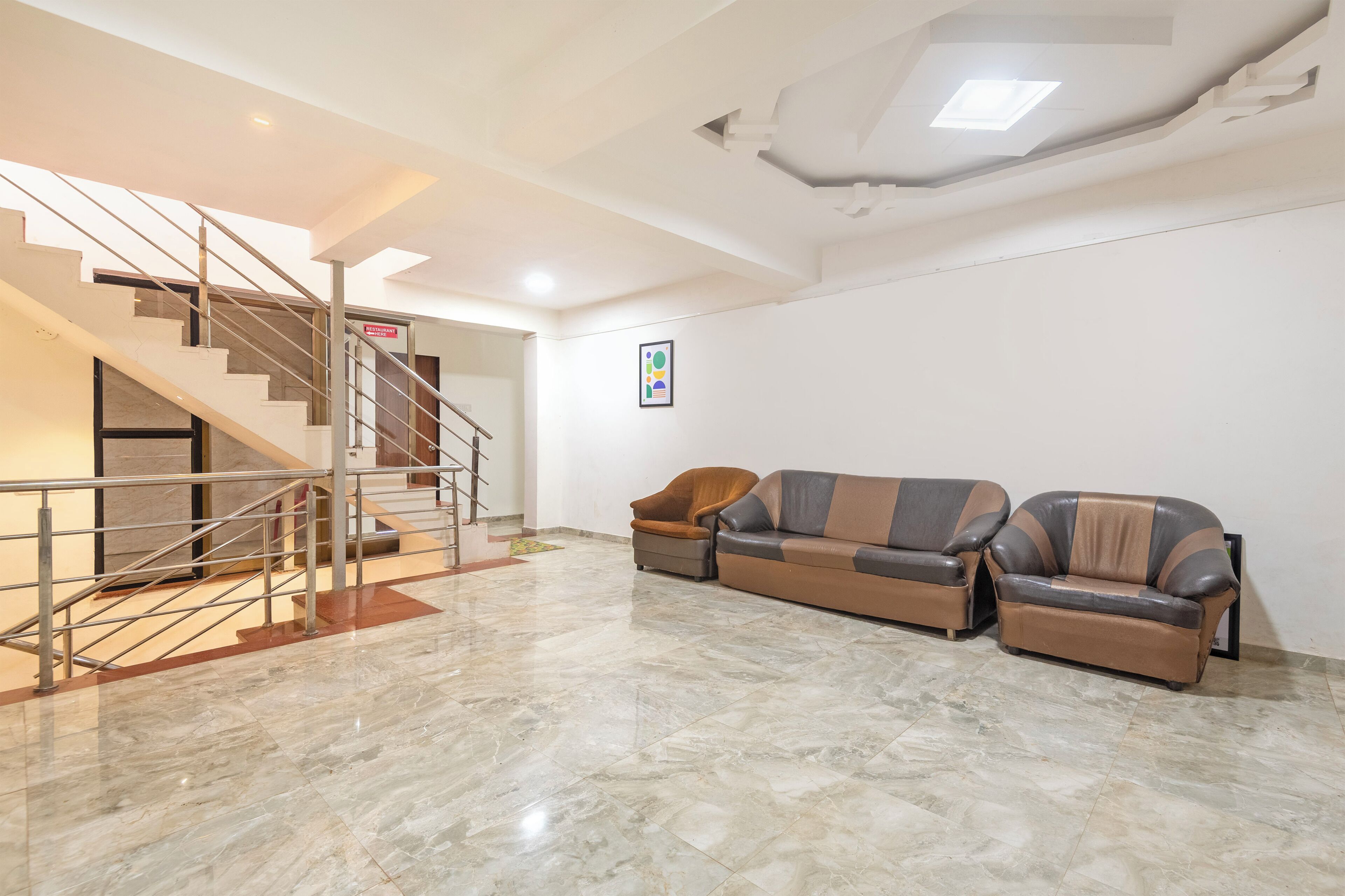 Un vestíbulo espacioso con piso de mármol, una escalera y dos sofás de cuero.