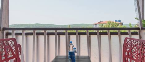 A balcony with a table, two chairs, a water bottle, and a metal tray.