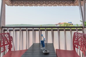 A balcony with a table, two chairs, a water bottle, and a metal tray. - Treebo Kuber Palace With a Swimming Pool (Mahabaleshwar)