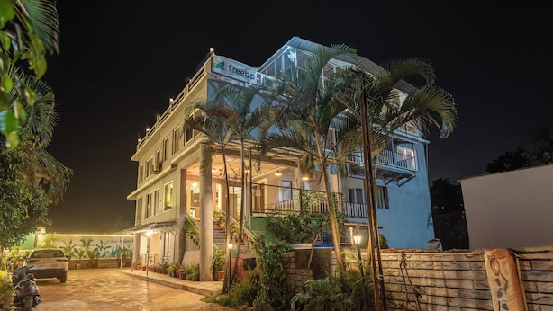 A two-story hotel with a balcony, a signboard, and a paved entrance. - Treebo Kuber Palace With a Swimming Pool (Mahabaleshwar)