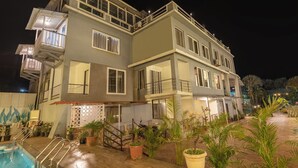 A two-story building with a swimming pool, potted plants, and a staircase leading to the entrance. - Treebo Kuber Palace With a Swimming Pool (Mahabaleshwar)