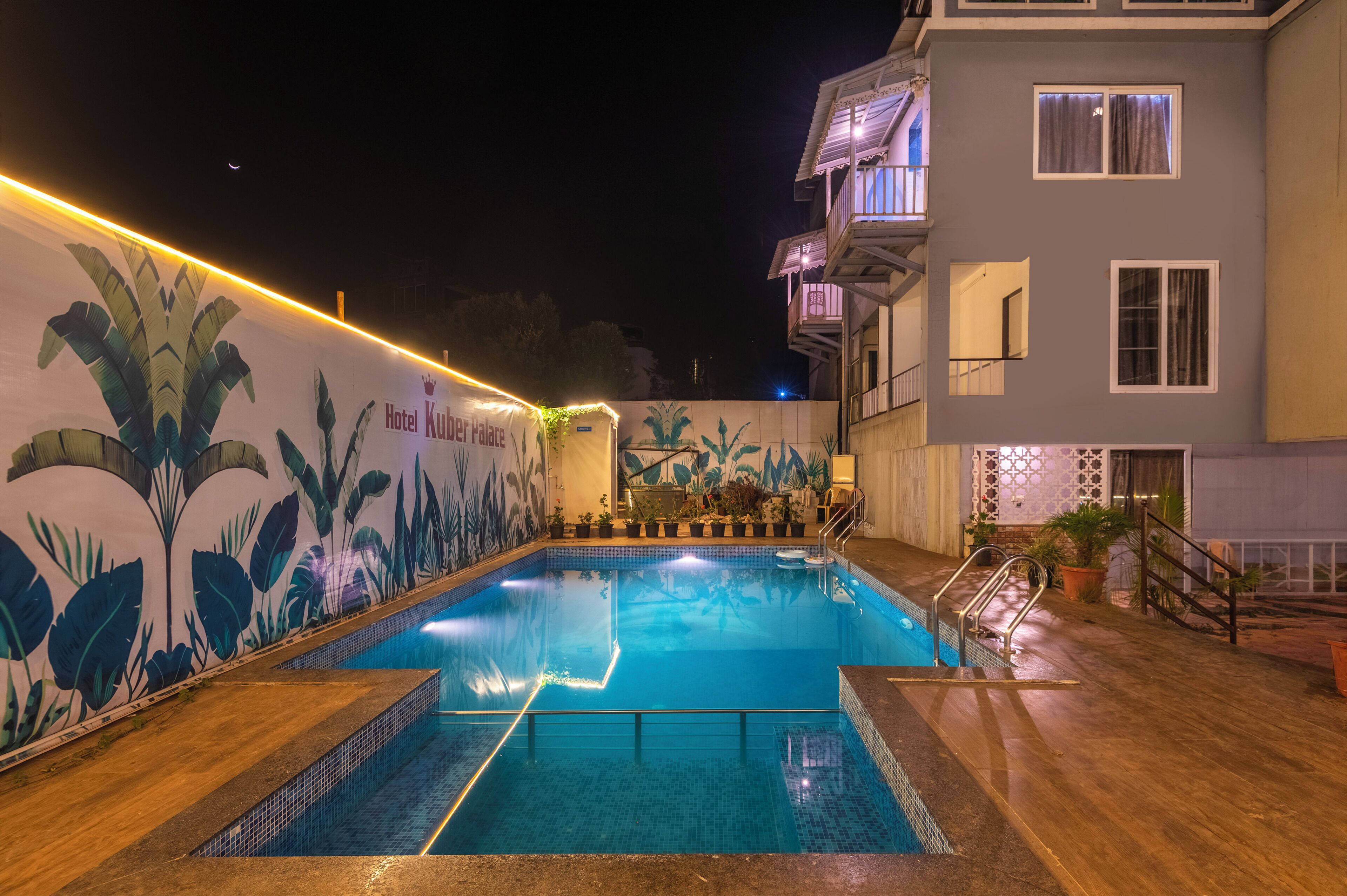 A swimming pool with a mural, a staircase, and a building with balconies.