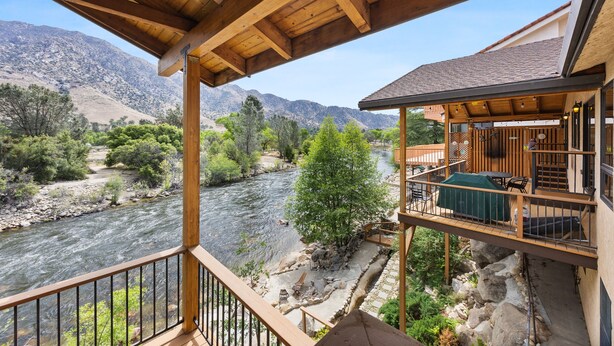 A wooden deck overlooking a river with mountains in the background.