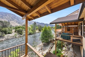 A wooden deck overlooking a river with mountains in the background.