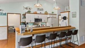 A modern kitchen with white cabinets, a central island with bar stools, and pendant lighting.