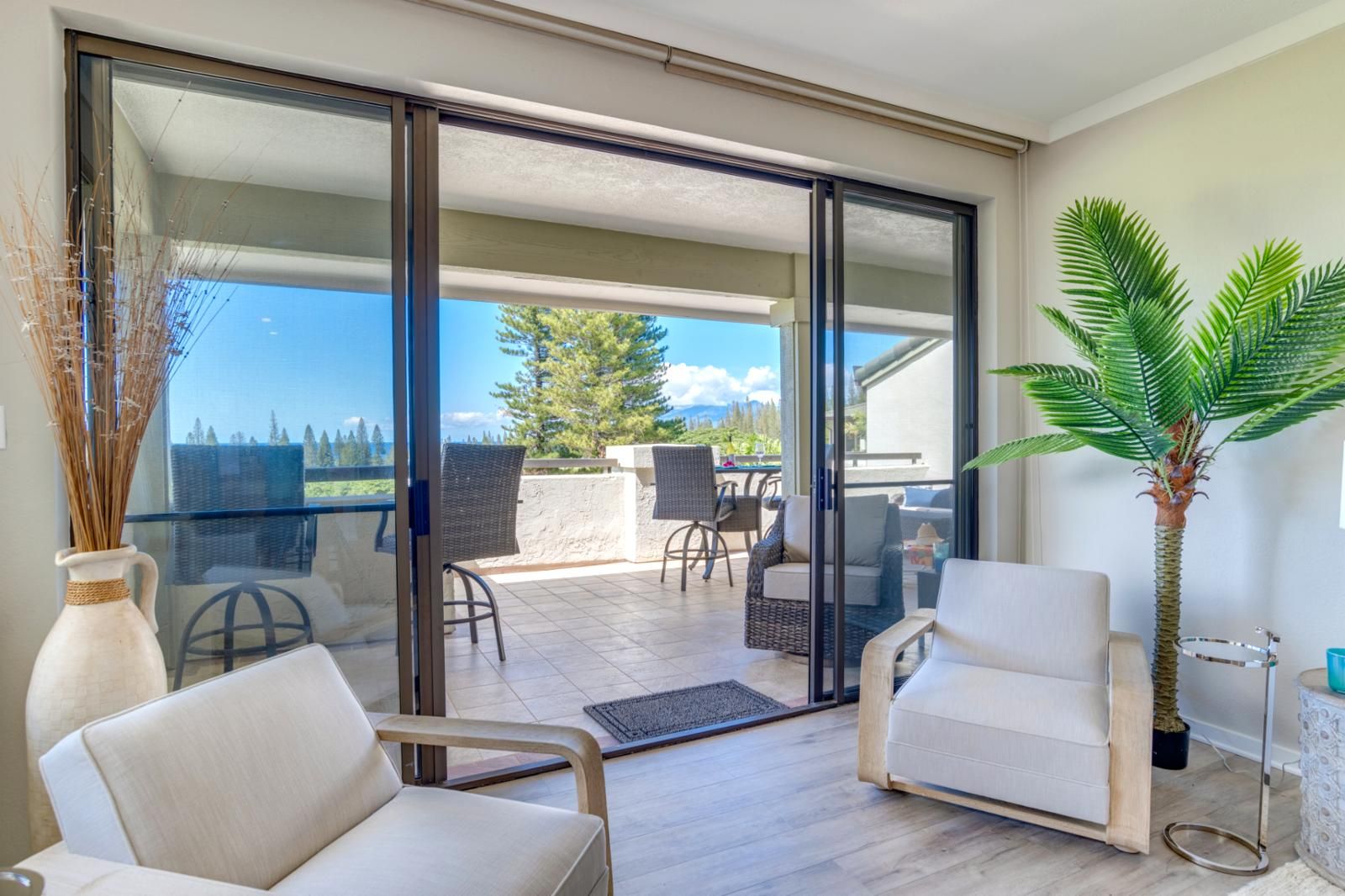 A balcony with a glass door, wicker furniture, a potted plant, and a view of the outdoors.