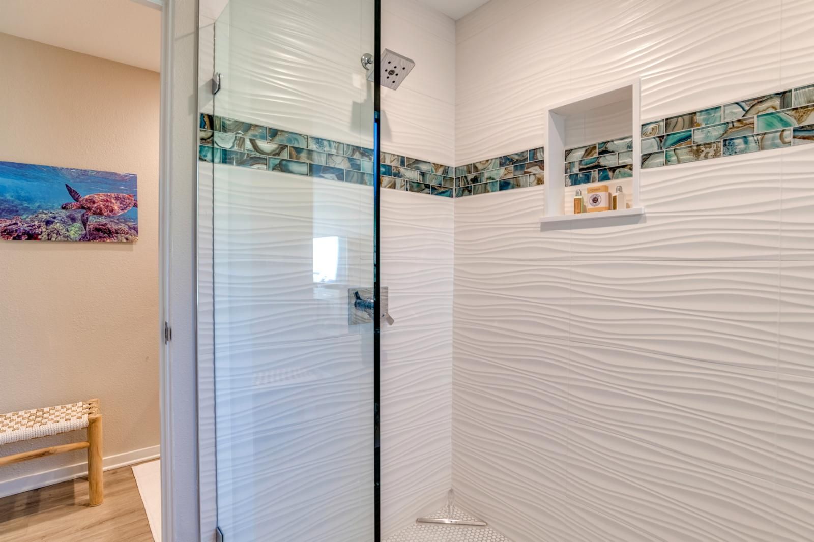 A bathroom with a glass door, a bench, and a mosaic tile backsplash.